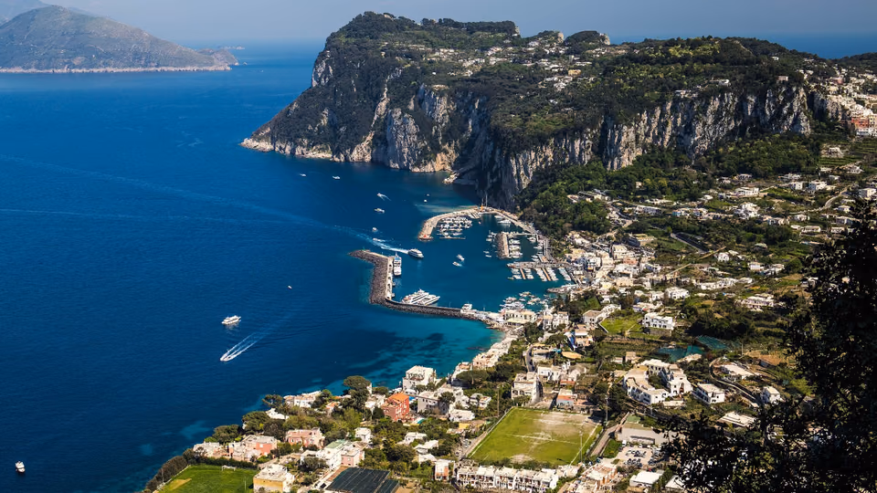 Blick von oben auf den Hafen von Capri und die Steilküste am tiefblauen Meer